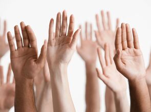 A close up of multiple people raising their hands denoting an answer to a question. 